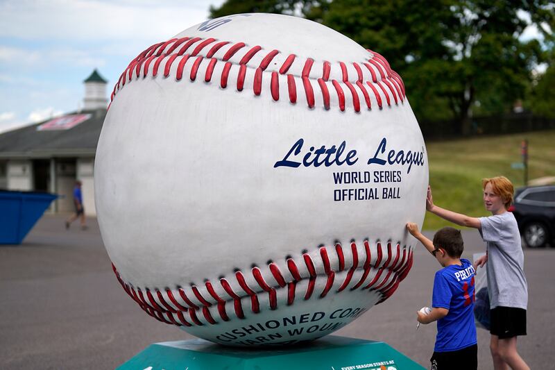 Fans touch a giant baseball outside of the Little League World Series baseball tournament in South Williamsport, Pa., in 2022.