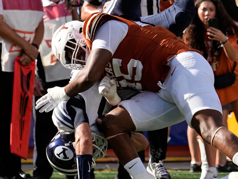 BYU quarterback Kedon Slovis, left, is upended by Texas defensive end Tausili Akana, right, during game in Austin, Texas, Saturday, Oct. 28, 2023.