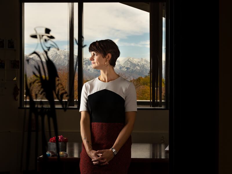 Dr. Angela Dunn stands with her head turned to the side and her back to a window with a decal of a plague doctor on it.