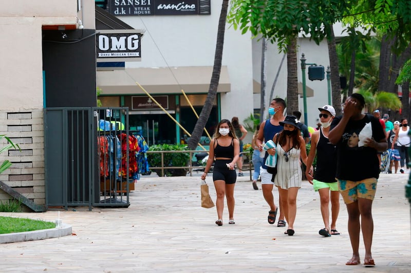 People walk past Waikiki restaurants and shops in Honolulu.
