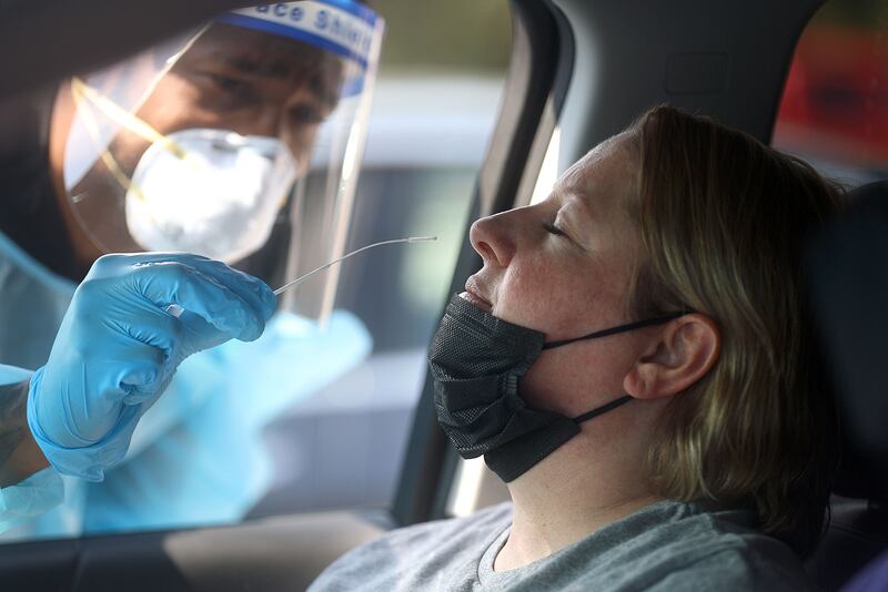 Frankie Coelho, a Nomi Health EMT, tests Angela Hiskey for COVID-19.