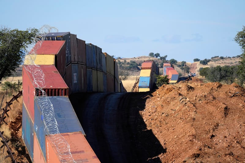 A long row of double-stacked shipping containers provide a wall between the United States and Mexico in San Rafael Valley, Ariz.