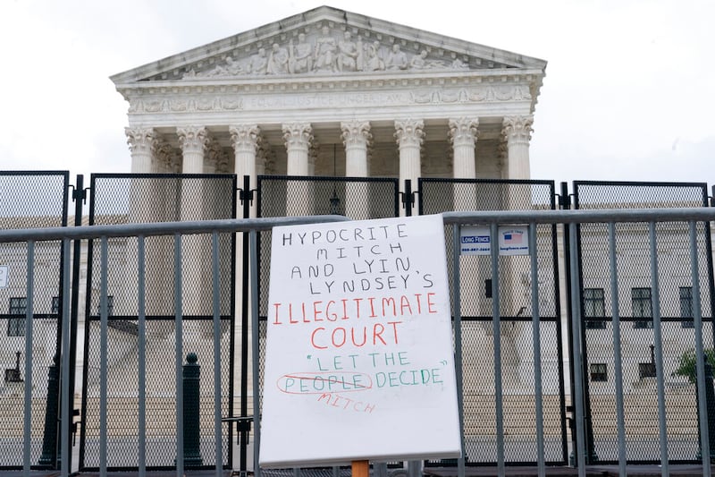 A protest sign is seen leaning on fencing outside the Supreme Court.