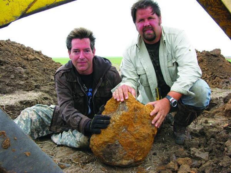 "Meteorite Men" Steve Arnold, left, and Geoff Notkin sit with one of their finds — a big rock from outer space.
