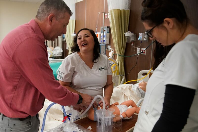 Dominique Elder, a student and respiratory therapist assistant at Utah Valley University, middle, laughs, as classmate Mica Alden, right, watches lab instructor Steve Panton demonstrate the steps of neonatal continuous positive airway pressure therapy on a mannequin during a lab at Utah Valley University in Orem on Thursday, Sept. 30, 2021.