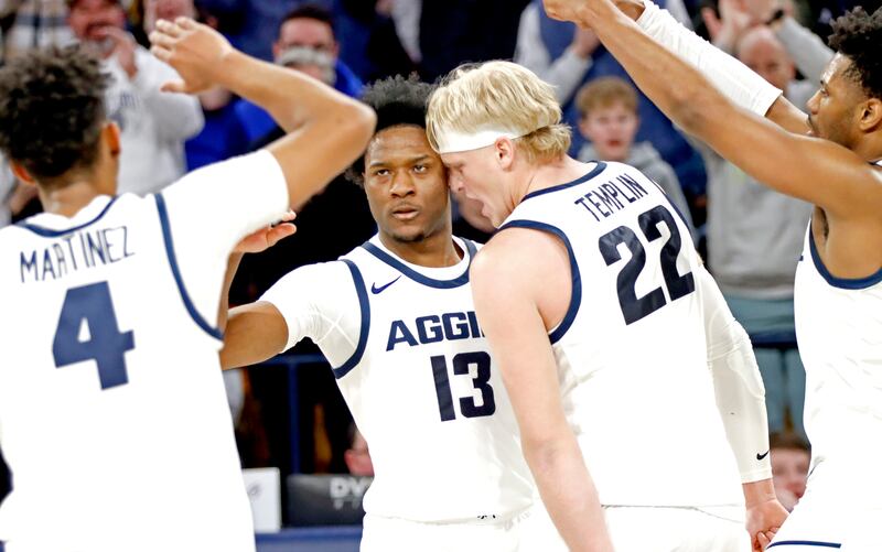 Aggie teammates Ian Martinez (4), Karson Templin (22) and Dexter Akanno help Utah State guard Deyton Albury (13) celebrate a score during USU's loss to New Mexico on Feb. 1, at the Spectrum in Logan.
