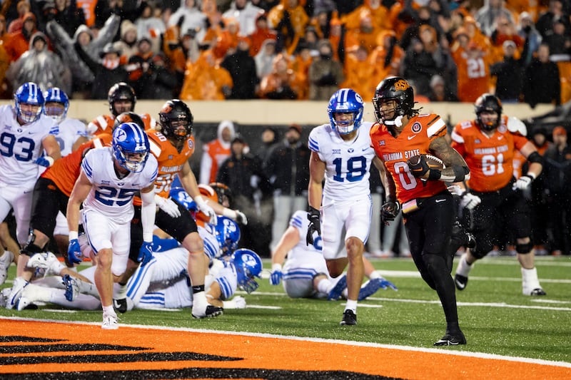 Oklahoma State running back Ollie Gordon II (0) runs past BYU defenders for a touchdown in overtime of a game Saturday, Nov. 25, 2023, in Stillwater, Okla.
