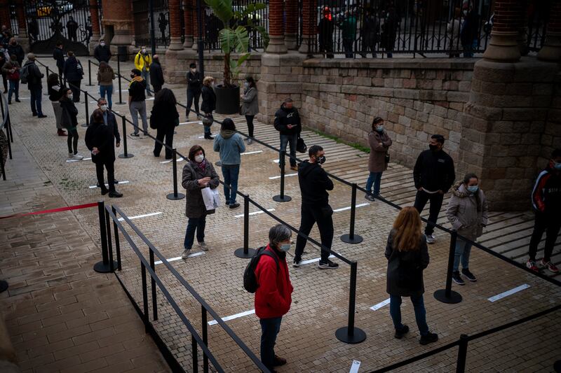 In this Dec. 1, 2020, file photo, people wait their turn to be called for a PCR test for the COVID-19 outside a hospital in Barcelona, Spain. Scientists say there is reason for concern but not alarm about new strains of the coronavirus, especially the one currently spreading in England.