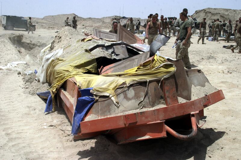 U.S. troops stand by large metal dumpster buried and used to store a large weapons cache near Karmah in Iraq’s al-Anbar province.