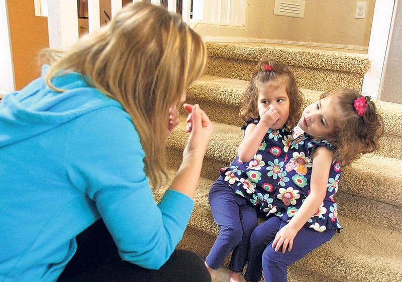 In this Jan. 13, 2010 file photo, Mandy Bailey, left, plays with her conjoined twin daughters Taylor and Emma in their San Tan Valley, Ariz. home. The 3-year-old twins died on Aug. 10, 2010 from heart-surgery complications in Seattle, a month before their