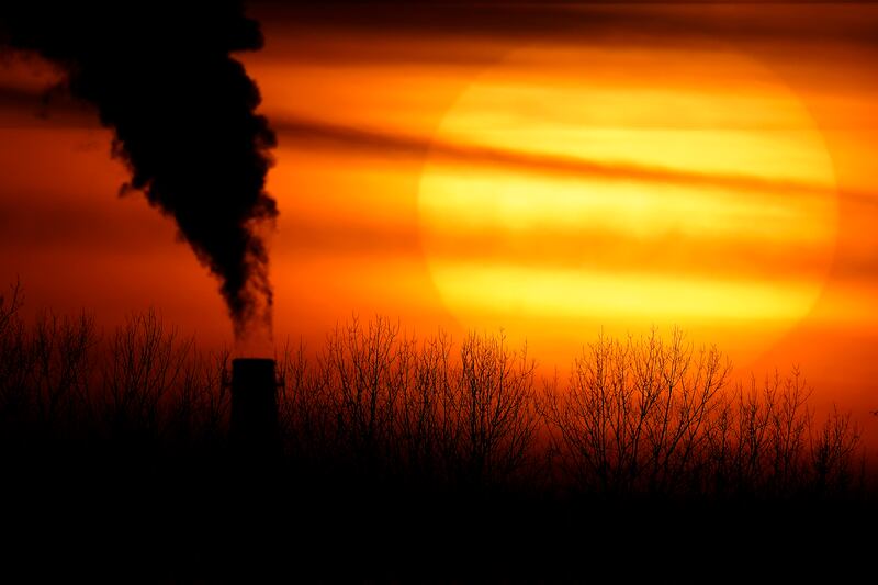 Emissions from a coal-fired power plant are silhouetted against the setting sun in Kansas City.