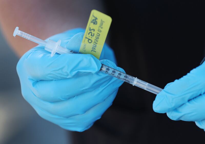 A syringe with a booster COVID-19 vaccine is held by a Nomi Health worker in West Valley City, Utah.
