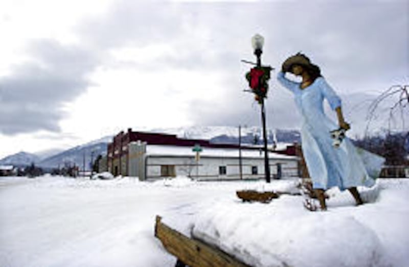 With the Wallowa Mountains in the background, a bronze statue of a woman bracing against the wind adorns the sidewalk in Joseph, Ore.