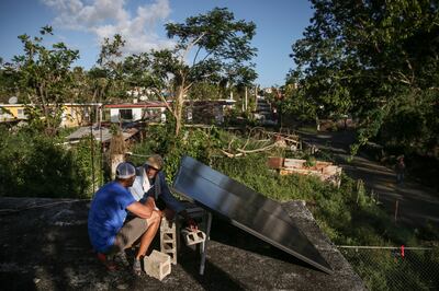 Luisito Rivera, a Light Up Puerto Rico volunteer, left, talks to Jose Muñoz Ortiz as they install solar panels on the roof of his home in Juana Díaz, Puerto Rico, on Saturday, Dec. 9, 2017.