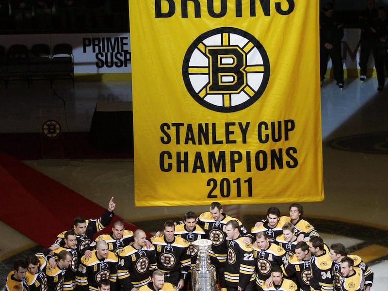 Boston Bruins players pose with the Stanley Cup and championship banner prior to facing the Philadelphia Flyers on opening night in an NHL hockey game in Boston, Thursday, Oct. 6, 2011.