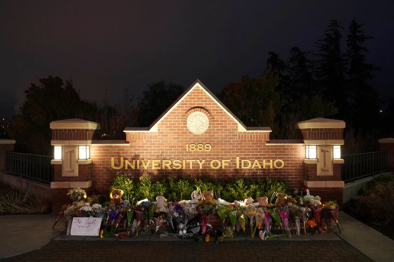 Flowers and other items are displayed at a growing memorial in front of a campus entrance sign for the University of Idaho.