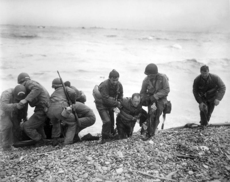 FILE - In this June 6, 1944, file photo, members of an American landing unit help their comrades ashore during the Normandy invasion. The men reached the zone code-named Utah Beach, near Sainte- Mere-Eglise, on a life raft after their landing craft was hi