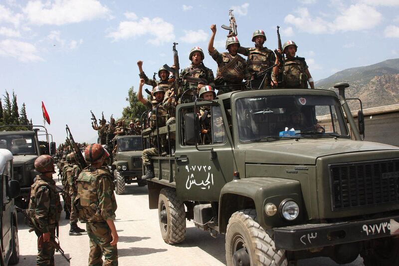 This Friday, June 10, 2011 file photo taken during a government organized tour for the media, shows Syrian army soldiers standing on their military trucks chanting slogans in support of Syrian President Bashar Assad, as they enter a village near the town