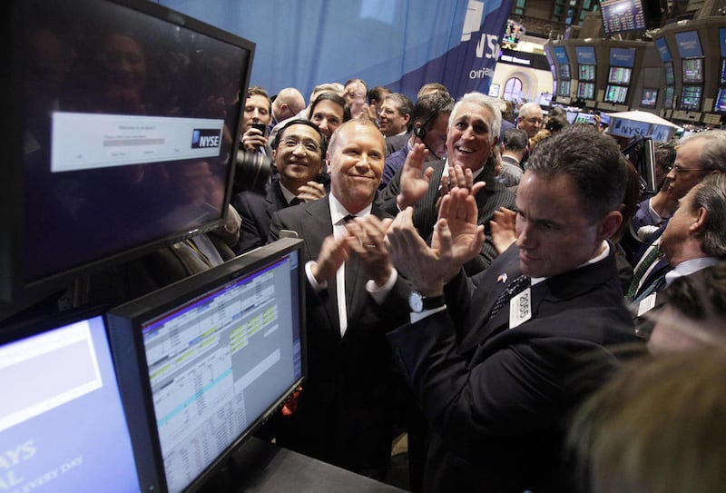 Fashion designer Michael Kors, center, applauds with Silas K. F. Chou, left, and Lawrence S. Stroll, third left, as the IPO of Michael Kors Holdings Ltd, begins trading on the floor of the New York Stock Exchange, Thursday, Dec. 15, 2011. The designer's c