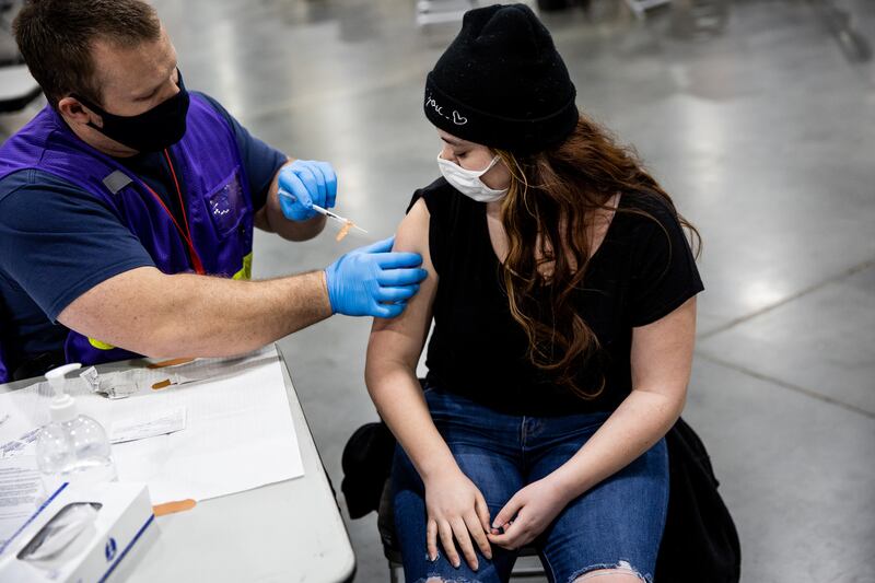 Ryan Marble, a firefighter paramedic with the Murray Fire Department, gives Mary Griego her first dose of the Pfizer-BioNTech COVID-19 vaccine