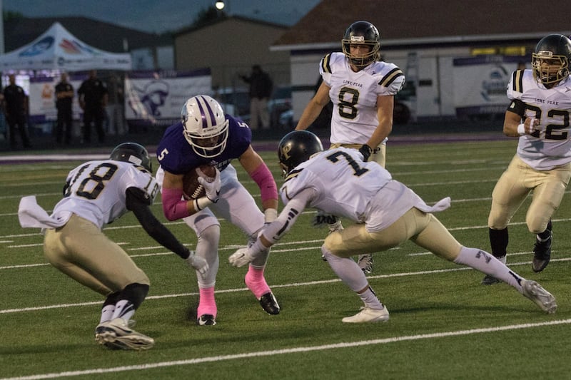 Lehi's Dallin Holker (5) stopped by Tommy Valletta (18) and Beau Peterson (7).  (Lone Peak vs Lehi 41-14 October 7, 2016)
