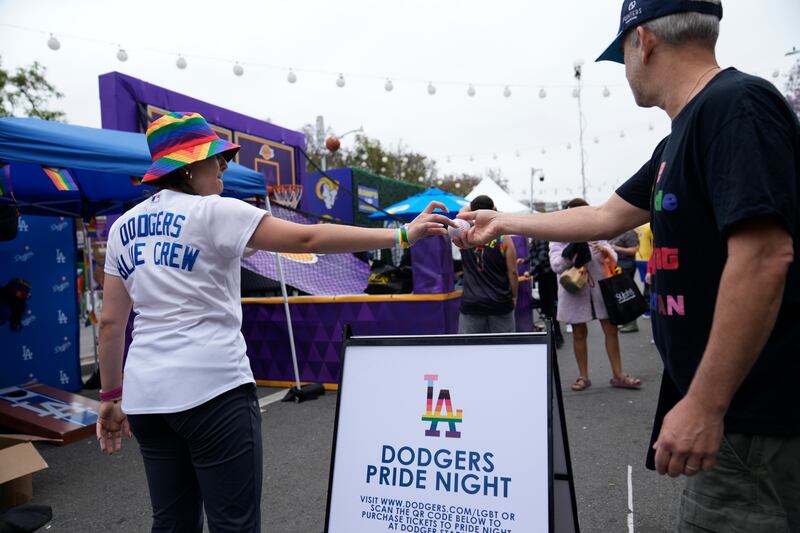 A Los Angeles Dodgers Pride promoter gives a ball to a participant at the WeHo Pride Parade in West Hollywood, Calif.