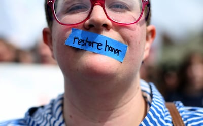 Anne Foley wears tape with the words "restore honor" over her mouth during a demonstration at BYU in Provo on Friday, April 12, 2019, calling for reform of the university's honor code and how it is enforced.