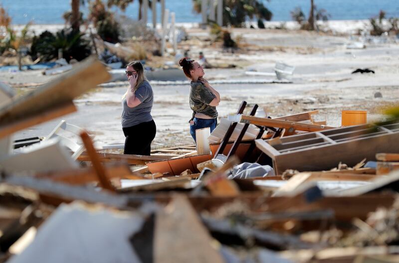 Christina Amanda, right, and Connie Huff wait for an insurance adjuster as they look for their possessions at the site of their destroyed home in the aftermath of Hurricane Michael in Mexico Beach, Fla., on Wednesday, Oct. 17, 2018.