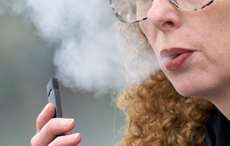 FILE - In this April 16, 2019 file photo, a woman exhales while vaping from a Juul pen e-cigarette in Vancouver, Wash. Schools have been wrestling with how to balance discipline with treatment in their response to the soaring numbers of vaping students.