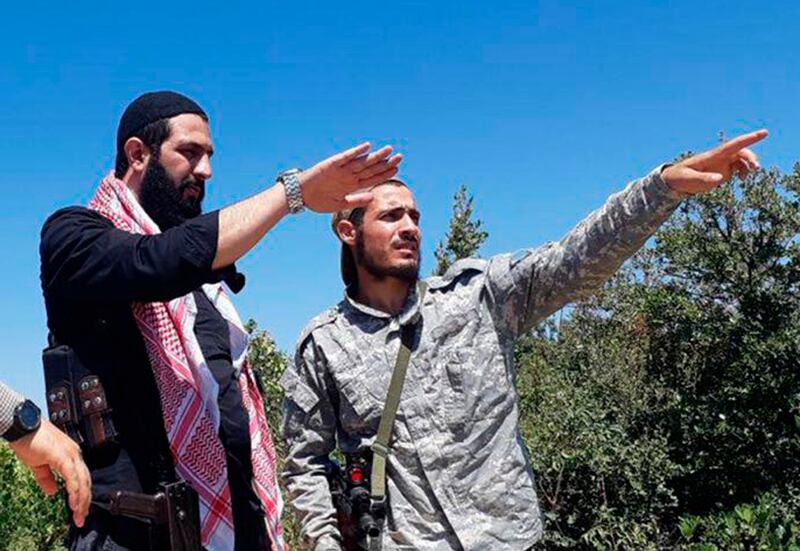 This undated photo released by the militant group Levant Liberation Committee on Tuesday, Aug. 21, 2018, shows Abu Mohammed al-Golani of the militant Levant Liberation Committee and the leader of Syria's al-Qaida affiliate, left, talking with a fighter, i