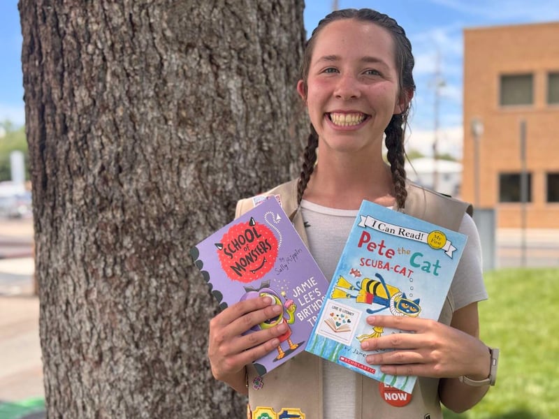 Claire McDaniel poses for a picture near Farmington, New Mexico, with books she has collected to help children learn to read as part of a Girl Scout project in 2025.