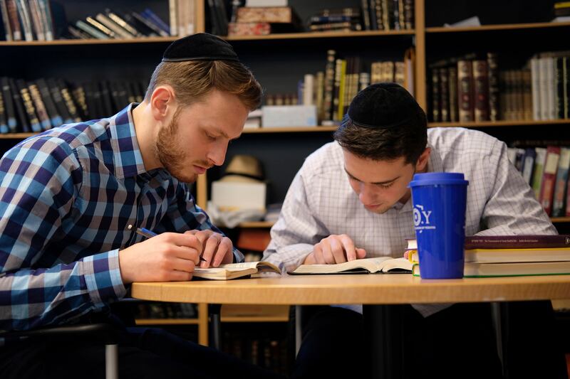 Yeshiva University students Aaron Heideman, left, and Marc Shapiro study in the university’s library in New York on Dec. 12, 2019.
