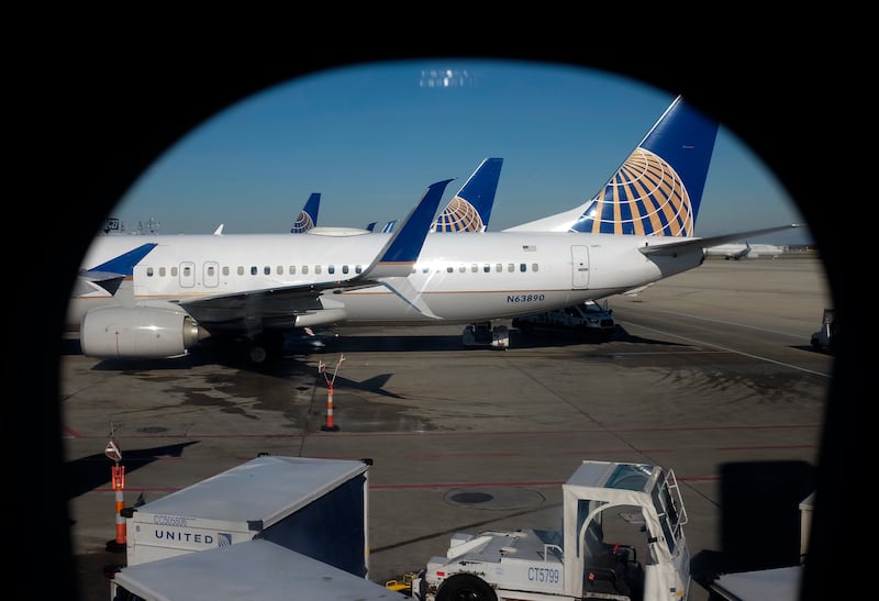 United Airlines planes are parked at a terminal at O’Hare International Airport, seen through an aircraft passenger window.