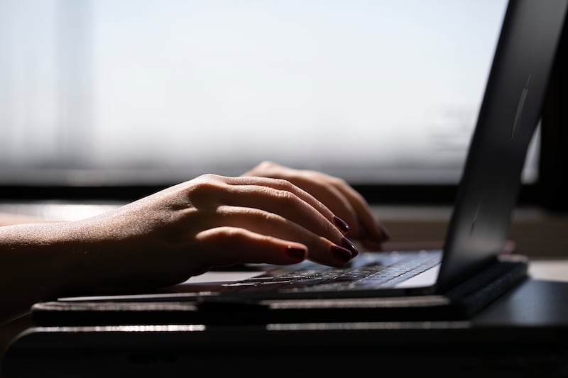 A woman typing on a laptop on a train in New Jersey.