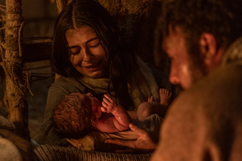 Young mother Mary, played by Sara Anne, holds baby Jesus as Joseph, played by Raja Bond watches in a scene of “Christmas With the Chosen: The Messengers.”