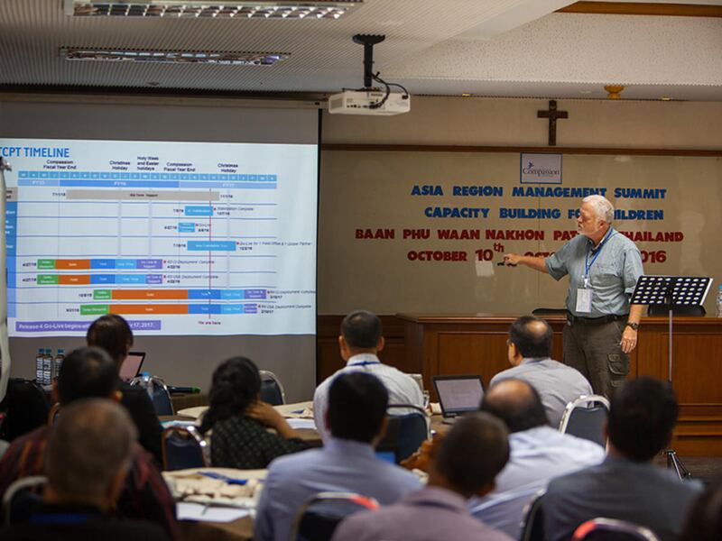 Ed Anderson, Compassion International's chief financial officer, discusses information systems with ministry workers in Thailand in October. The ministry's field offices in 26 countries work with nearly two million children.