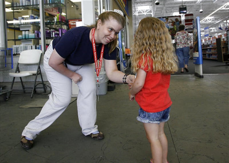 Wal-Mart greeter Elise Hansen, left, gives a sticker to 3-year-old Tatem Criddle at the Wal-Mart in Clearfield on Friday. Hansen was born a conjoined twin 31 years ago.