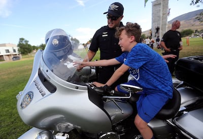 Unified police officer Zack Young shows Brayden Zambos a police motorcycle during a Night Out Against Crime at Pleasant Green Park in Magna on Monday, Aug. 5, 2019.