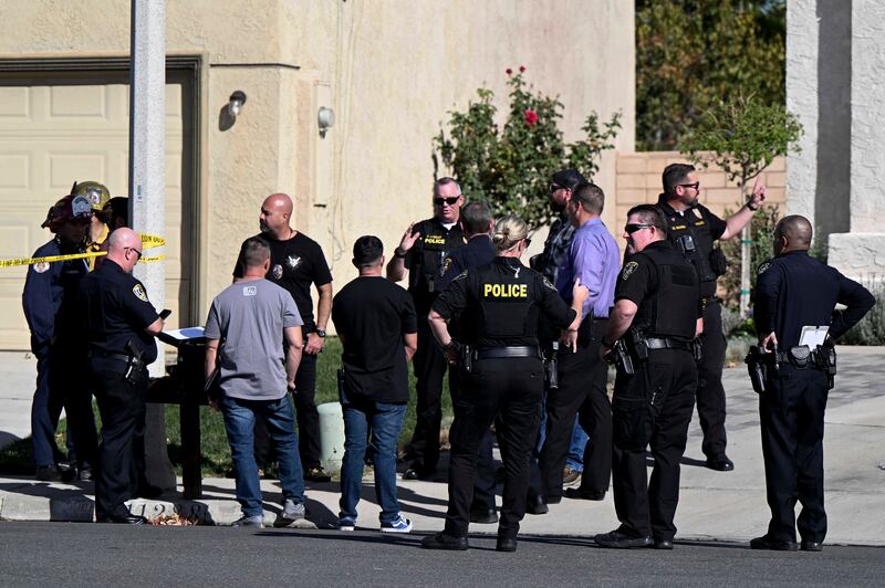 Firefighters and Riverside Police gather outside a burned home in Riverside, Calif.