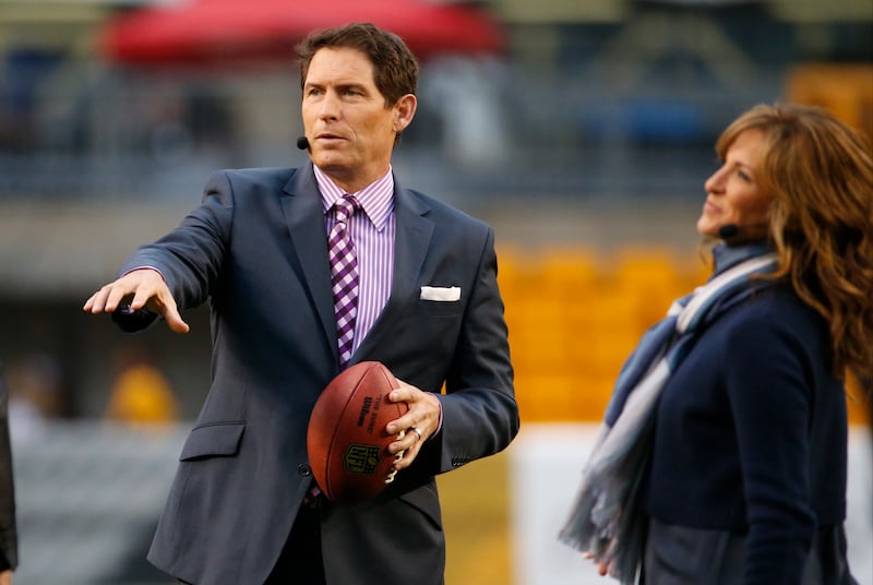 Steve Young holds a football and talks with other broadcasters before an Oct. 20, 2014, game.