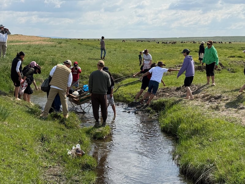 Latter-day Saint youth and leaders participate in trek, pulling a handcart through mud during the June 13 and 14, 2025, trek near Ulaanbatar, Mongolia.