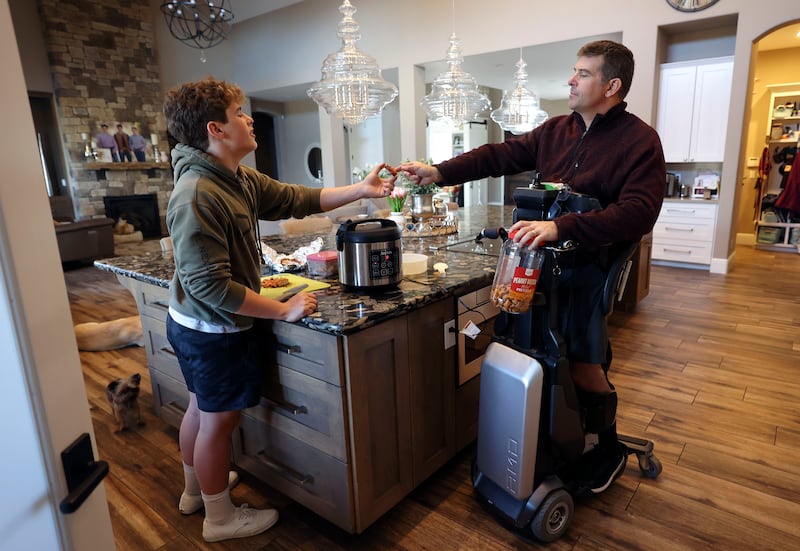 Jed Winchester gives his father, Bill Winchester, a piece of chicken as Bill uses his Tek RMD at their home in Reno, Nevada,
