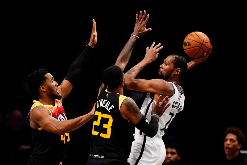 Brooklyn Nets’ Kevin Durant, right, passes away from Utah Jazz’s Donovan Mitchell, left, and Royce O’Neale during the second half of an NBA basketball game Monday, March 21, 2022 in New York. The Nets won 114-106. (AP Photo/Frank Franklin II)
