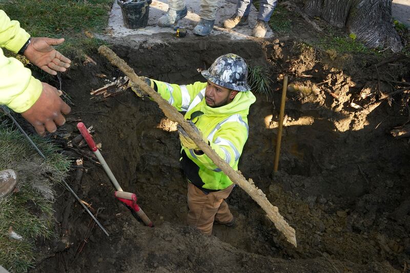 A cut lead pipe is pulled from a dig site for testing at a home in Royal Oak, Michigan.