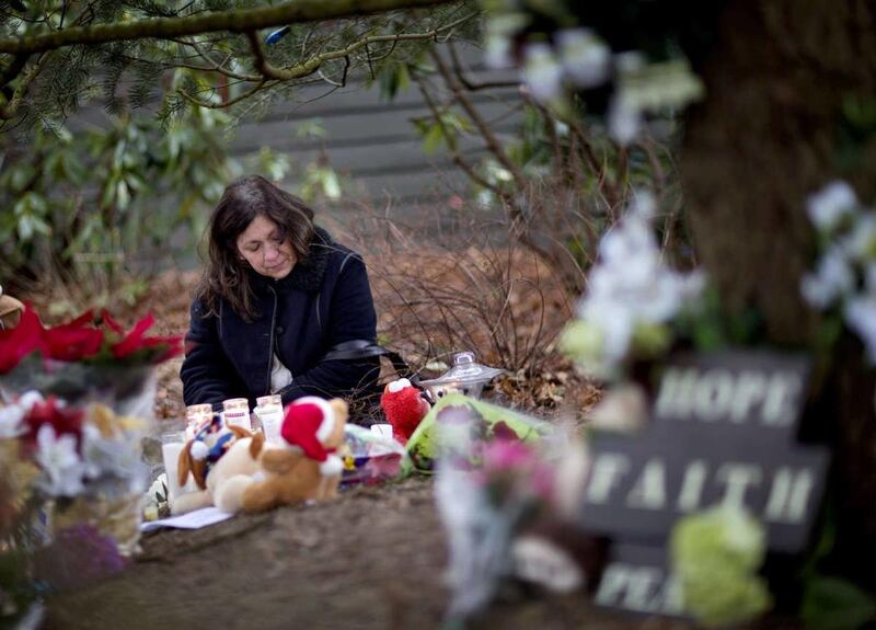 Dilma Steiner, of Newtown, Conn., visits a sidewalk memorial for the Sandy Hook Elementary School shooting victims, Sunday, Dec. 16, 2012, in Newtown, Conn. A gunman walked into Sandy Hook Elementary School in Newtown Friday and opened fire, killing 26 pe