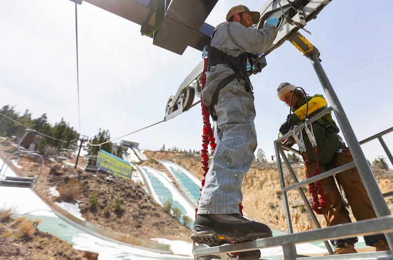 Lift operators Jack Gayton and Ben Marmer add grease to a wheel on the Nordic Chairlift at the Utah Olympic Park.