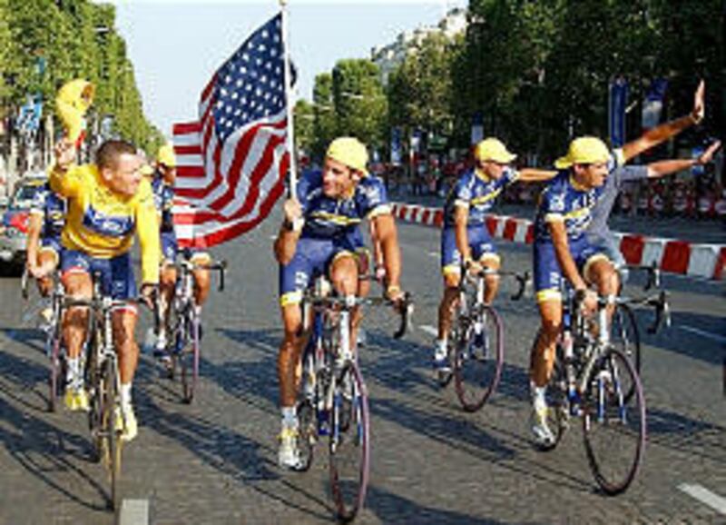 Lance Armstrong, left, rides with George Hincapie of the U.S., holding the flag, and other teammates.