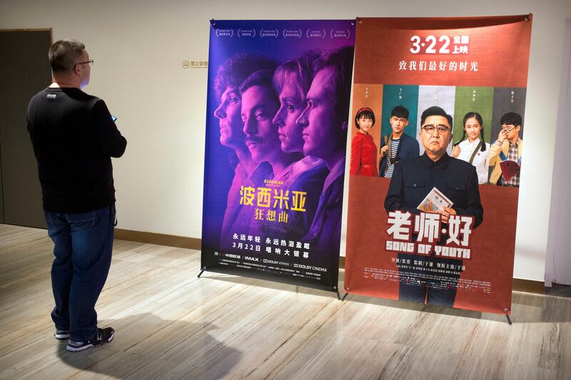 A customer looks at a movie poster for the film “Bohemian Rhapsody” at a movie theater in Beijing, Wednesday, March 27, 2019. Moviegoers in China say the version of the “Bohemian Rhapsody” shown in Chinese theaters erases mentions of Freddie Mercury’s sexuality. The biopic on the lead singer of the British rock band Queen omitted a same-sex kiss and lacked scenes in which Mercury reveals he’s not straight and has AIDS. (AP Photo/Mark Schiefelbein)