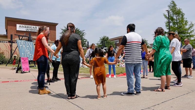 People hold hands as they pray at a memorial for victims of a mass shooting, May 9, 2023, in Allen, Texas.