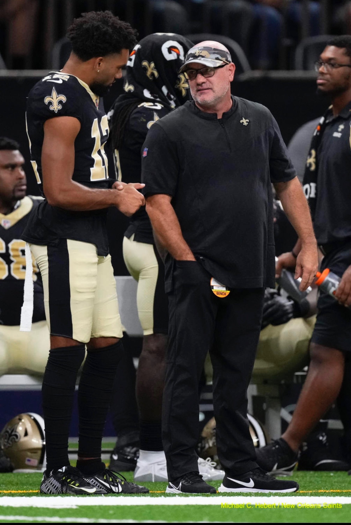 New Orleans Saints “athletic engineer” Matt Rhea, right, talks with Saints receiver Chris Olave on the sidelines during game in New Orleans.